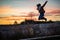 Beautiful woman jumping from a concrete block during sunset