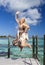 beautiful woman jumps up on a wooden platform over the sea