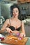 Beautiful and woman in the kitchen. Smiling brunette preparing food. Young girl wearing black bra cutting some onions