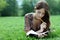 Beautiful woman lays on a grass in park with a diary in ha