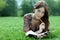 Beautiful woman lays on a grass in park with a diary in ha