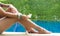 Beautiful woman legs. Sunbathing near swimming pool and hand holding white flower.