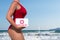 Beautiful woman lifeguard in a red swimsuit with a first aid kit on the sea and surfers background