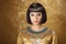 Beautiful woman like Egyptian Queen Cleopatra on golden background