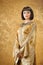 Beautiful woman like Egyptian Queen Cleopatra on golden background