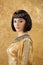 Beautiful woman like Egyptian Queen Cleopatra with serius face on golden background