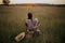 Beautiful woman in linen dress sitting on chair with book and enjoying sunset in summer meadow