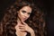 Beautiful woman with long brown curly hair. Closeup portrait with a pretty face of the young girl. Fashion model with manicure