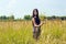 Beautiful woman with long dark hair standing in sunny cornfield