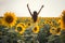 Beautiful woman with long hair hands up in a field of sunflowers