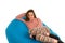 Beautiful woman lying on blue beanbag sofa isolated on white background