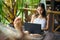 Beautiful woman lying in a hammock with laptop in a tropical res