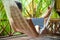 Beautiful woman lying in a hammock with laptop in a tropical res