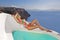 Beautiful woman lying on a pool of the view of the sea in a swimsuit color in santorini