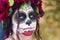 Beautiful woman in makeup traditional Mexican Calavera skull Katrina in the autumn forest, in a wreath of red flowers. Day of the