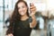 Beautiful woman manager smiling holding brochure in one hand and car keys in another standing in dealership center