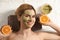 Beautiful woman with mask on face and cut orange relaxing