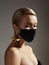 Beautiful woman with medicine mask on face. Fashion eye make-up, gold jewelry. Protection hygiene in virus pandemic