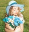 Beautiful woman with multi colored bouquet of daisies on the field background with blue butterflies close up