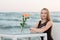 A beautiful woman near the sea on blue sky background in summer. Gorgeous stylish young woman rests near blue lagoon.