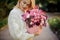 Beautiful woman neatly holds pink round box with flowers inside