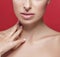 Beautiful woman nose lips and shoulders touching her neck by fingers close up studio portrait on red