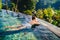 Beautiful woman in outdoors swimming pool. Holiday concept with woman sunbathing in infinity swimming pool