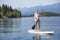Beautiful woman paddle boarding on scenic mountain lake