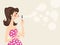 Beautiful woman in pink dress blowing soap bubbles