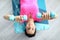 Beautiful woman in pink T-shirt lie on gymnastic mat and rais her arms with dumbbells up above herself.