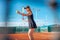 A beautiful woman plays tennis on the court. Sporting black dress suit. The girl smiles, happy. The athlete delivers the