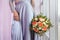 Beautiful woman in a plum dress holding a bouquet of roses, closeup detail shoot, focus on flowers
