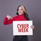 Beautiful woman pointing at a Cyber Week sign against a grey background