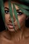 Beautiful woman portrait on black background. Young afro girl posing with green leaves and closed eyes. Gorgeous make up.