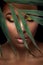 Beautiful woman portrait on black background. Young afro girl posing with green leaves and closed eyes. Gorgeous make up.