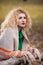 Beautiful woman posing in park during autumn season. Blonde girl wearing green blouse and big shawl posing outdoor. Long fair hair