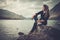 Beautiful woman posing on the shore of a wild lake, with mountains on the background.