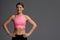 Beautiful woman posing in studio. Portrait of happy young brunette in pink top for yoga or fitness, she stands on gray