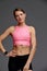 Beautiful woman posing in studio. Portrait of happy young brunette in pink top for yoga or fitness, she stands on gray