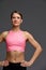 Beautiful woman posing in studio. Portrait of happy young brunette in pink top for yoga or fitness, she stands on gray