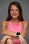 Beautiful woman posing in studio. Portrait of happy young brunette in pink top for yoga or fitness, she stands on gray