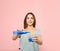 Beautiful woman pouring mouthwash from bottle into glass on color background. Teeth care