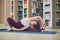 Beautiful woman practices yoga asana Parivrtta Janu Sirsasana - breakdown pose in the library