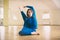 Beautiful woman practices yoga sitting twisted asana Marichiasana in the yoga studio