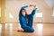 Beautiful woman practices yoga sitting twisted asana Marichiasana in the yoga studio