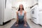 Beautiful woman practicing yoga, exercising in small home room kitchen, tiny home, cramped apartment