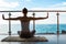 The beautiful woman practicing yoga sitting on a rug and stretching your hands on a balcony with the seaside view.