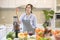 Beautiful woman is preparing healthy fresh juice, while vegetables and juicers on the table in kitchen, health concept