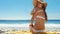 Beautiful woman putting on sunscreen at beach