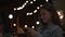 Beautiful woman reads message on background of lights of summer cafe. Media. Young woman looks at phone and smiles while